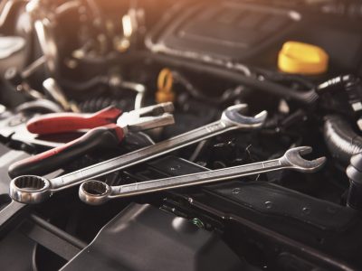 Mechanic hand checking and fixing a broken car in car service garage.